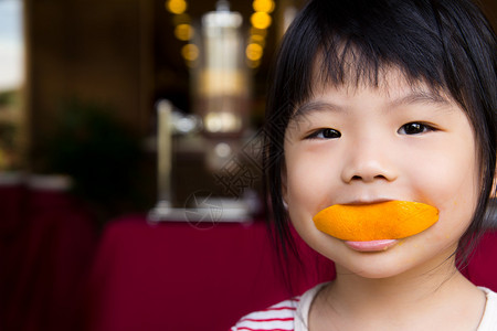 可爱的小女孩吃一片橙色背景图片