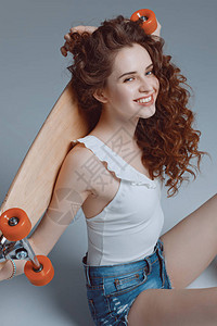 年轻时尚的时髦女孩坐在灰色的滑板上背景图片
