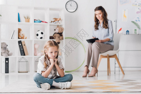儿童坐在地板上心理医生坐在背景上图片
