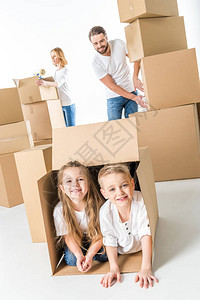 可爱的小孩笑在纸板盒里而父母则用白衣隔图片