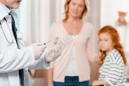 用注射器给诊所小女孩注射医用手套的医生图片