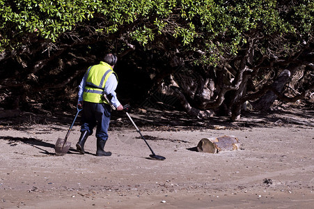 男子在海滩上用金属探测器寻找金属背景图片