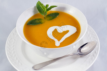 这是一碗南瓜汤的照片配有艺术心脏形状背景图片