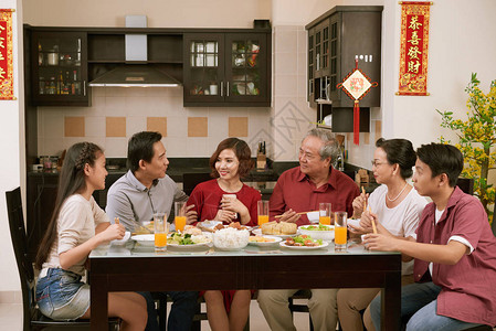亚洲大家庭在农历新年庆祝活动中交谈和吃东西图片