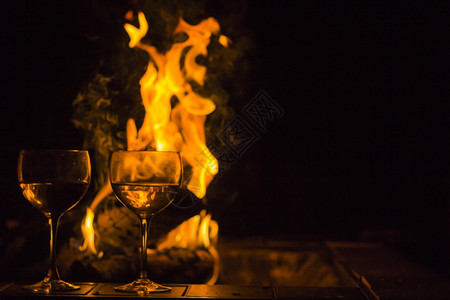两杯葡萄酒由营火旁的两杯红酒在这张闪亮背景图片