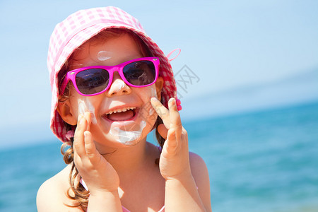 女孩在海滩上涂抹她的面部保护霜图片