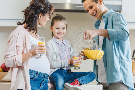 快乐的家庭父亲倒果汁在厨房背景图片