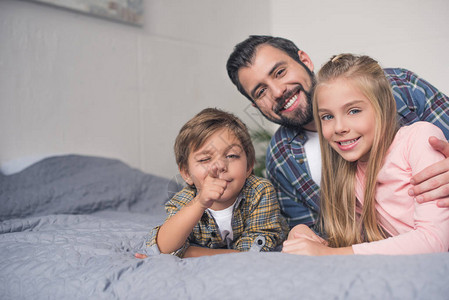 快乐的父亲和小孩的肖像在家里一起躺在床图片