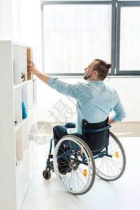 坐在轮椅上的残疾青年商人在办公室的架图片