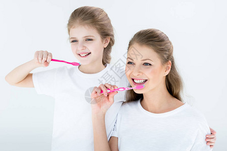 快乐的母女用白色牙刷清洁牙齿图片