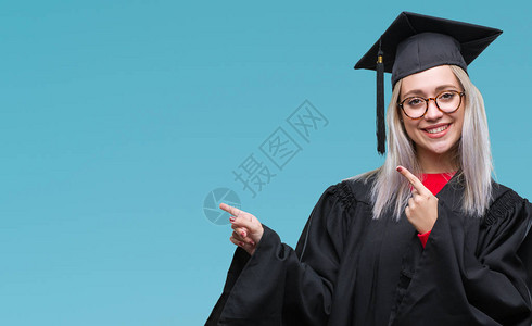 身穿研究生制服的金发年轻女子在孤立的背景中微笑地看着镜头图片