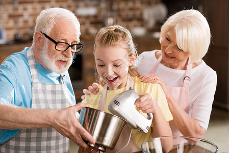 高老女人看着快乐的祖父和孙女把面粉混图片