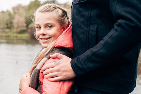 父亲和可爱快乐的小女儿站在公园里微笑着的镜头下图片