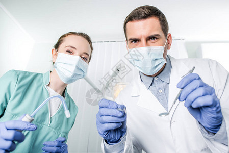 戴口罩的牙医手里拿着牙科器械图片