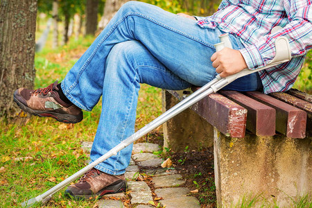 残疾人在公园的长凳上拄着拐杖图片