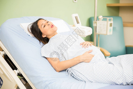 一位美丽的年轻孕妇在医院里试图呼吸以缓解分娩宫缩背景图片