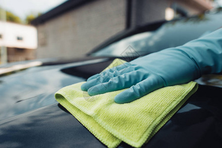 在橡皮手套用抹布擦洗汽车时看到图片