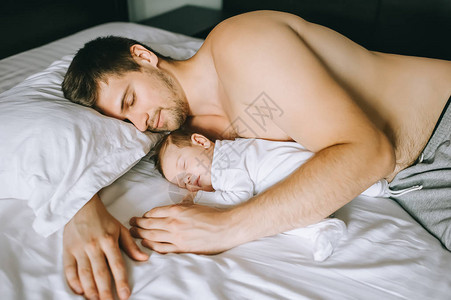可爱的小可爱男孩和不穿衣服的父亲一起睡图片