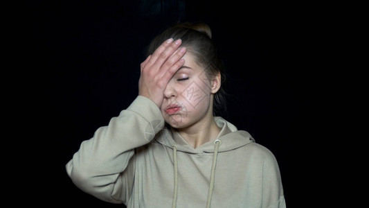 疲惫的年轻女子用手捂着脸不快乐和恼怒的年轻女人类的面图片