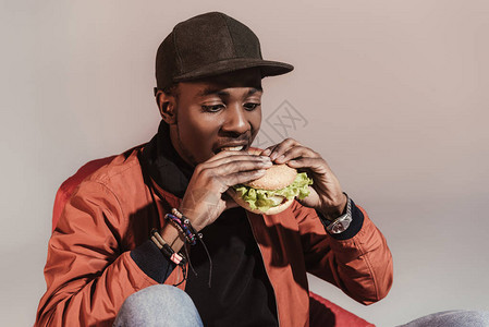 美国人吃汉堡包的年轻非洲男子孤背景图片