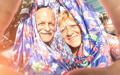 快乐的老夫妇在周游世界的服装市场自拍图片