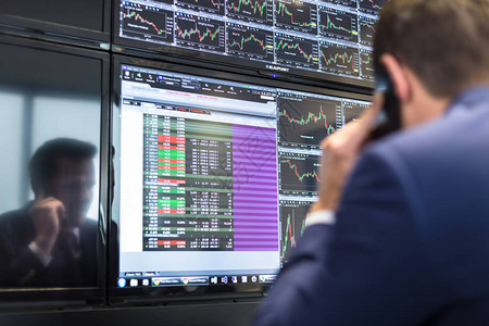 用手机交易股票的商人股票分析师在多个计算机屏幕上查看图表索引和数字股票交易员评估经济数据蓝色图片