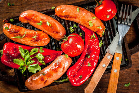 烧烤家庭热狗烤蔬菜香肠西红柿和辣椒放在烤盘上图片