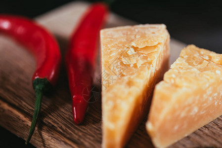 木制切菜板上美味帕尔马干酪和辣椒的特写视图图片