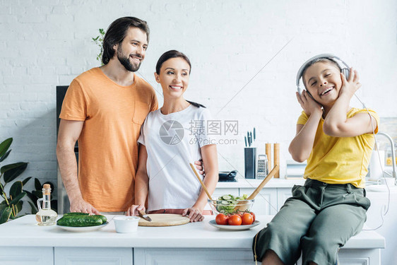 戴着耳机微笑的小女孩坐在桌子上图片