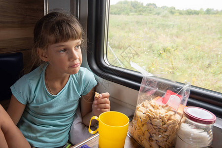 女孩在火车上吃饼干看着窗外图片