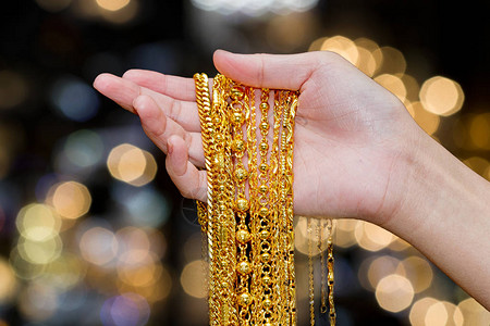 美丽的女人手握金项链首饰图片