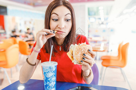 快乐的年轻女子在快餐厅吃汉堡包苏背景图片