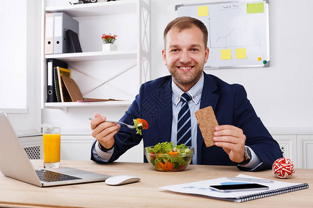 男人在现代办公室享用蔬菜沙拉的健康商务午餐图片
