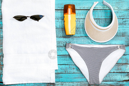 桌上毛巾泳裤太阳镜和防晒霜的俯视图图片