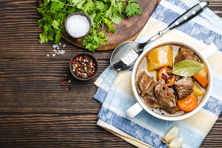 慢煮肉炖在碗里的特写镜头与牛肉土豆胡萝卜肉汤在木制质朴的背景图片