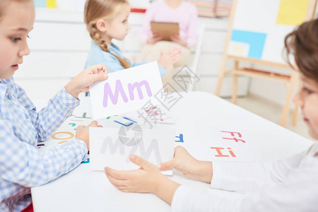 两个孩子在幼儿园或小学上课时选择纸牌和英文字母图片