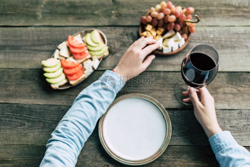 女人手里拿着一杯酒拿着奶酪的裁剪图像图片