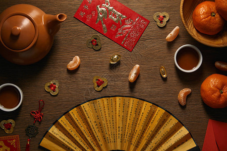 新鲜成熟的橘子茶具带象形文字的扇子和木桌上的金币的顶视图图片