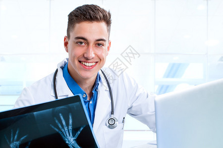 诊所用笔记本电脑和X光片拍摄年轻医科学生在书桌图片
