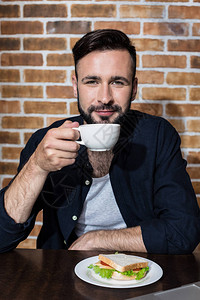 长着英俊胡子的年轻男子喝咖啡图片