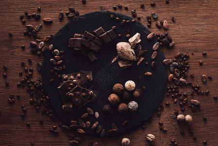 木桌上被可豆咖啡粒和肉豆蔻包围的各种巧克力片和松露的砧图片