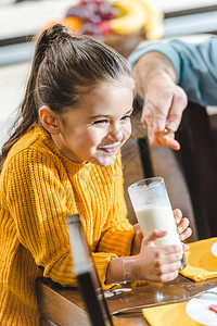 微笑的孩子坐在桌旁喝牛奶图片