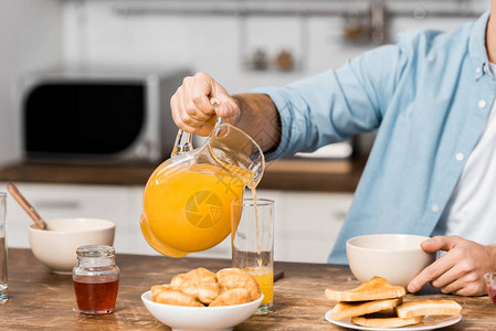 厨房桌上的玻璃杯中浇橙子汁的图片