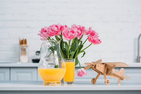 花瓶中的粉红郁金香橙汁和现代厨房桌图片