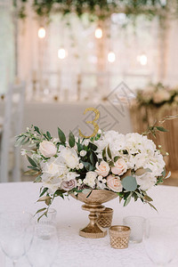 用金花瓶里的鲜花装饰婚礼上的宴会桌时尚餐厅桌图片