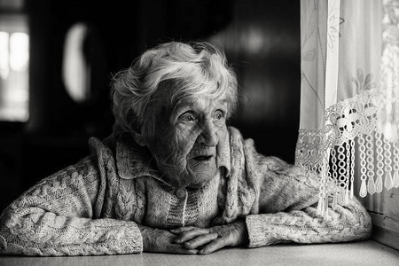 坐在窗户旁边的一位老年妇女的黑白肖图片