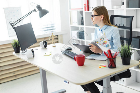 一个穿着白色T恤衫和黄外套的美丽红发年轻女孩正在一间明亮办公室工作照背景图片