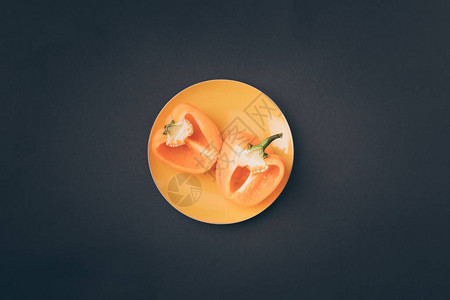 灰色黄盘子上两半黄色甜椒的顶部视图图片