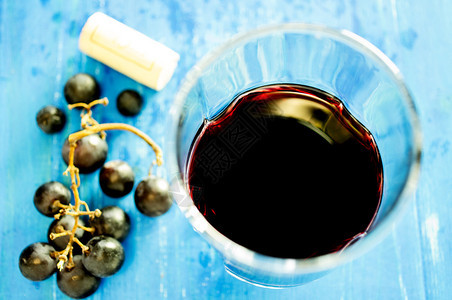 红葡萄酒杯在老木板上就在酒柜和背景图片
