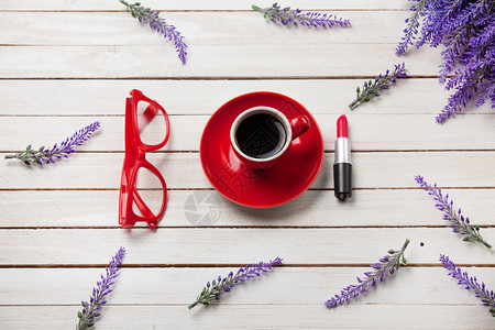 在白色木制背景上涂着口红和色眼镜的咖啡杯图片